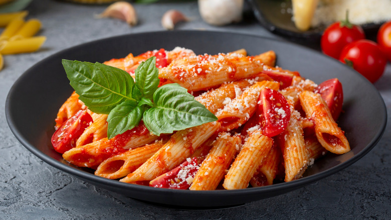 penne pasta in bowl with tomato based sauce and grated cheese