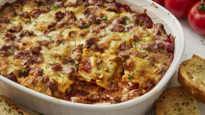 ravioli lasagna in casserole dish with garlic bread