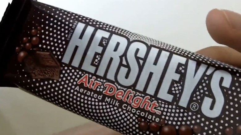 Hands holding a wrapped Hershey's Air Delight bar