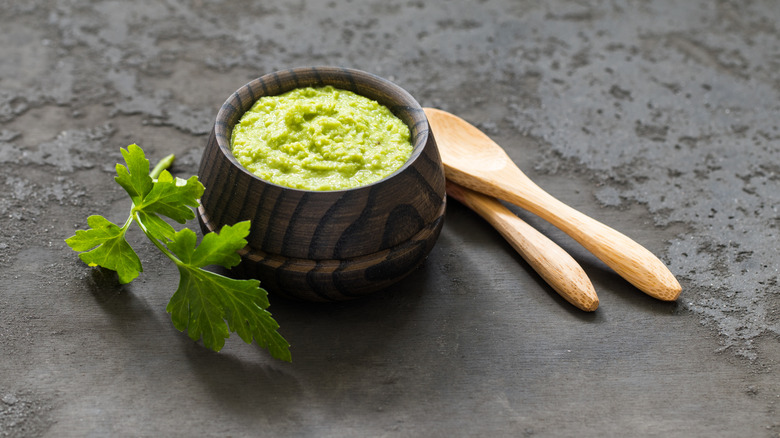 container of wasabi paste with wooden spoons and garnish