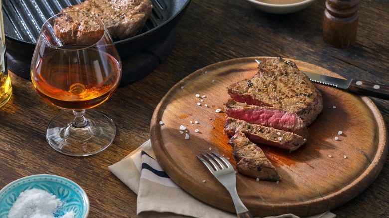 A glass of whisky with sliced steak