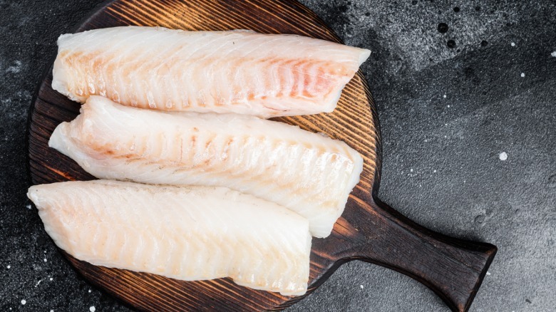 raw fillets of cod on a wooden board