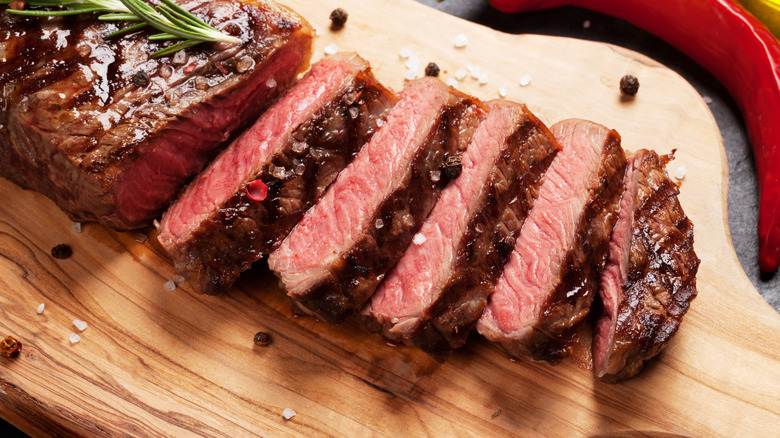 sliced medium steak on wooden board