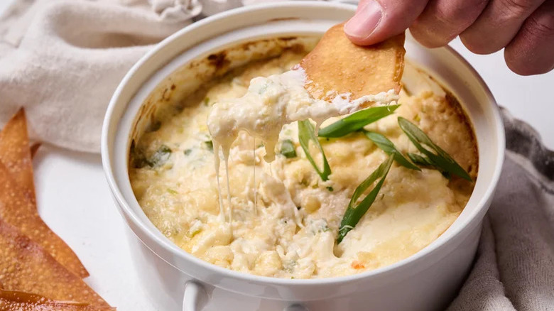 Person dipping chip in cheesy crab rangoon dip