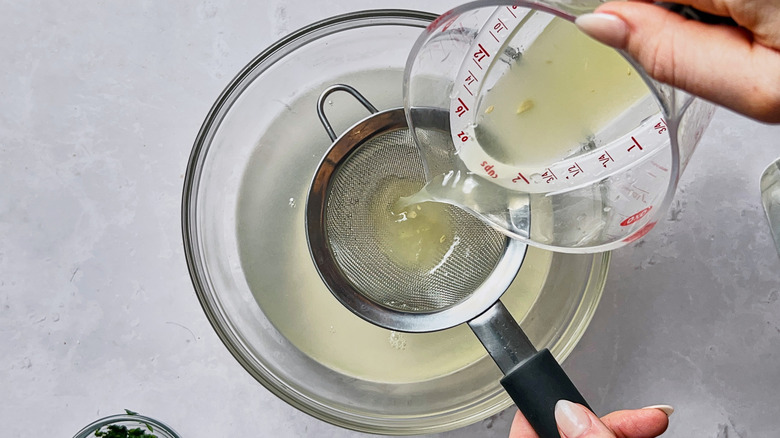 straining lemon juice into bowl