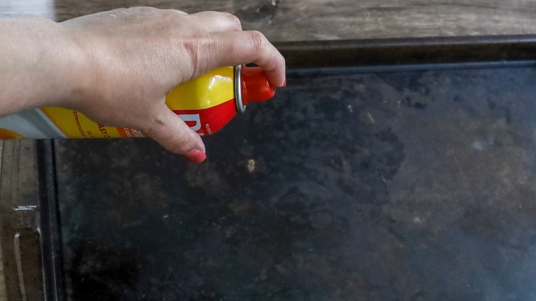 baking sheet being greased with cooking spray