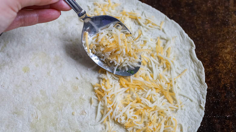 cheese being spooned onto a tortilla