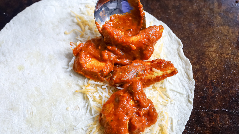 sauced chicken being added to a tortilla