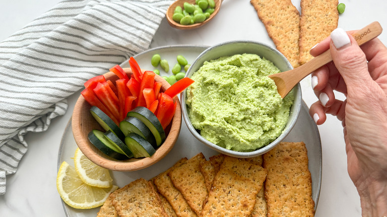 hand scooping out hummus