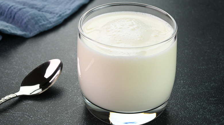 Glass of buttermilk next to a spoon