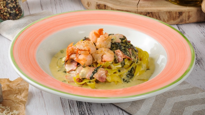 Shrimp and spinach pasta in a pink bowl