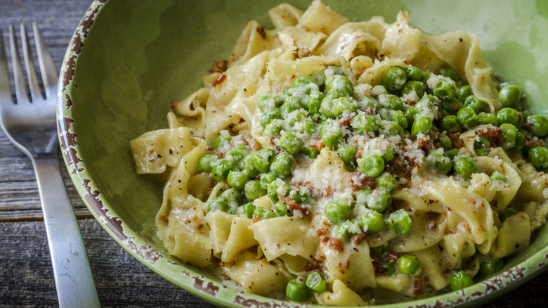 Linguini with peas and cheese served in green bowl