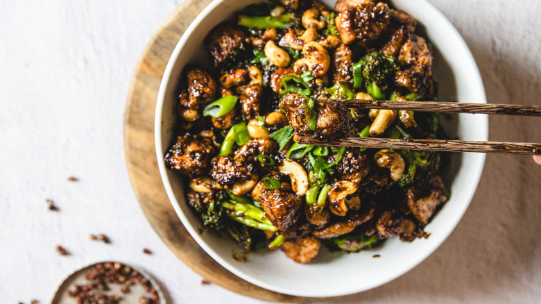 Lifting chicken in chopsticks over bowl