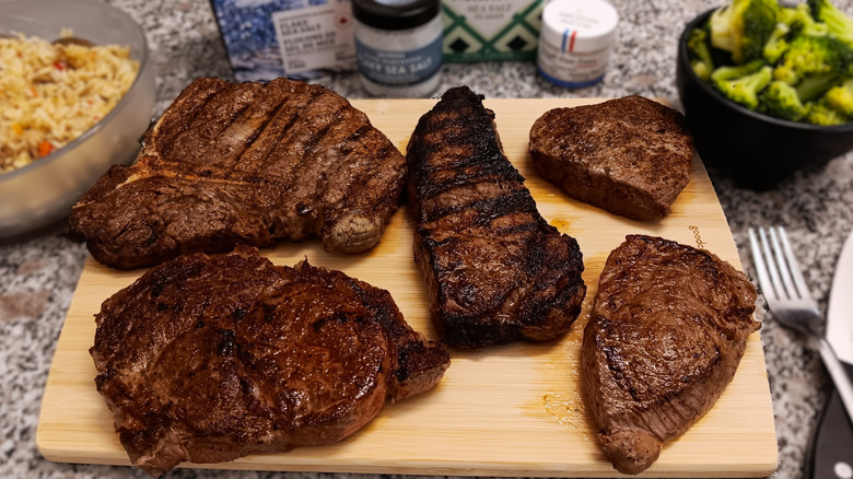 five different cuts of steak from LongHorn Steakhouse on cutting board with sides