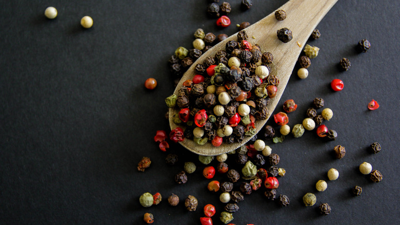 black peppercorns in wooden spoon