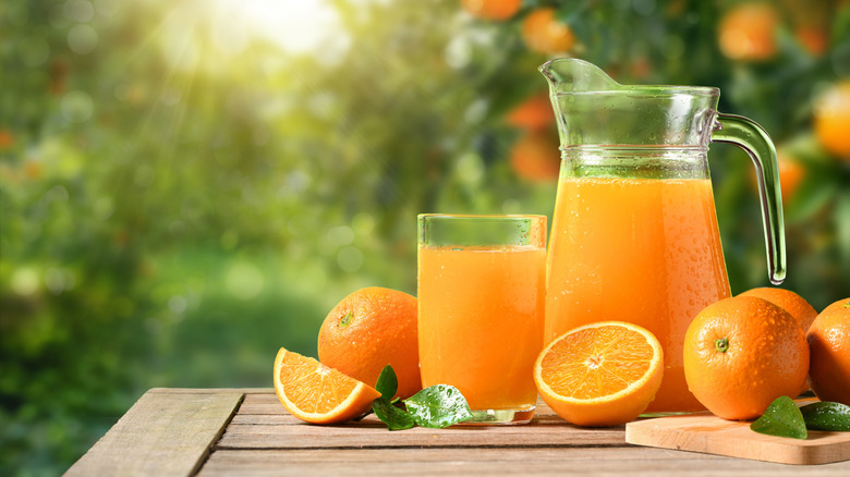 fresh orange juice outside with whole and sliced oranges