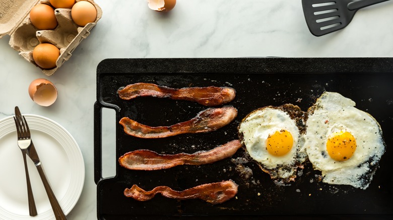 fried eggs and bacon on a griddle