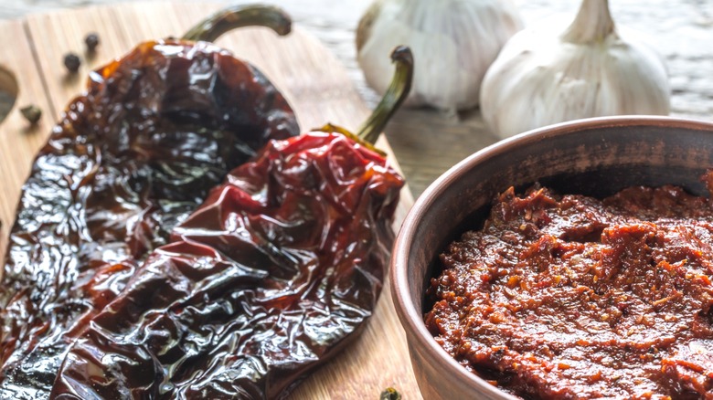 Dried chipotle peppers next to a bowl of adobo paste