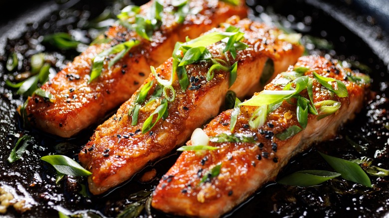 Three salmon filets glazed in soy sauce topped with scallions