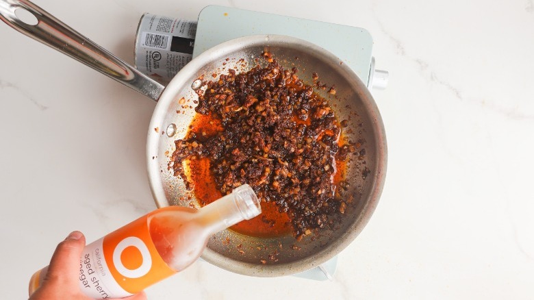 Pouring sherry vinegar into pan