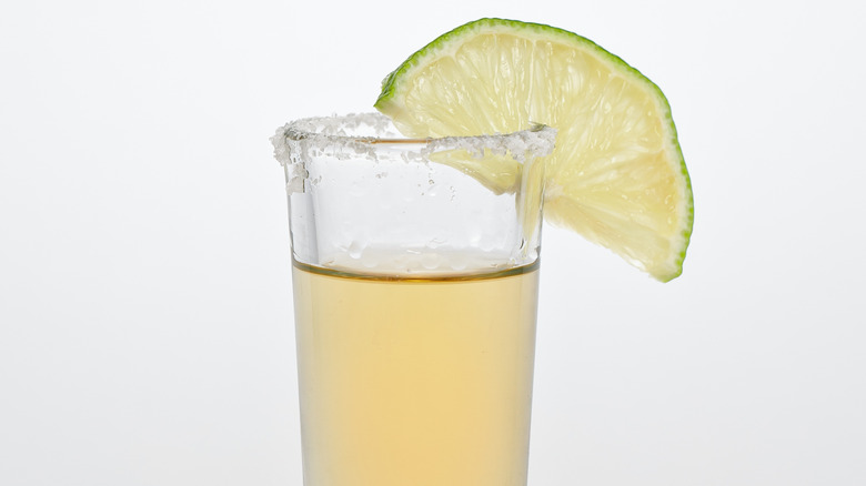 Close-up of tequila in a shot glass with salt and a lime wedge