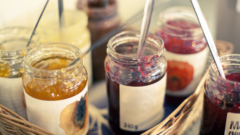 Several jars of fruit jam with spoons in them