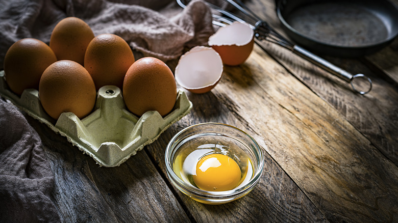 Egg yolk in glass bowl with half carton