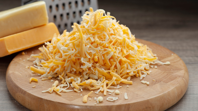 Shredded cheeses on wood board