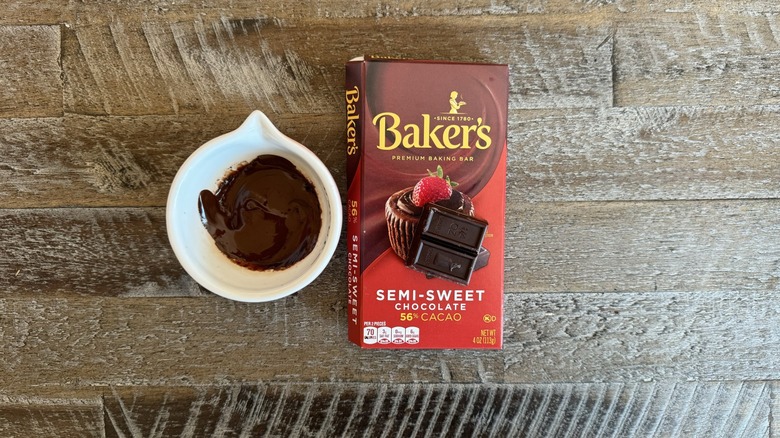 Baker's chocolate in a box sits next to a cup of melted chocolate.