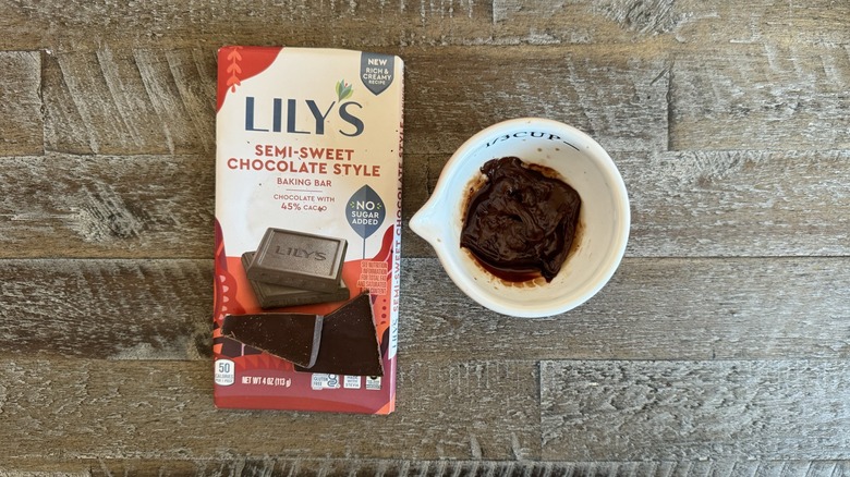 Lily's baking chocolate bar is in a package next to a cup of chocolate.