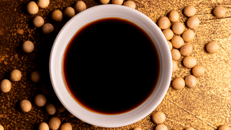 top view of a bowl of soy sauce with soy beans around it