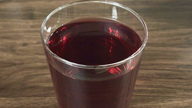 Closeup of glass of dark red hibiscus tea on coffee table