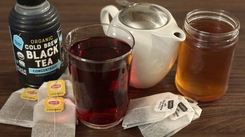 Assortment of tea bags, bottles, glasses of tea, and teapot