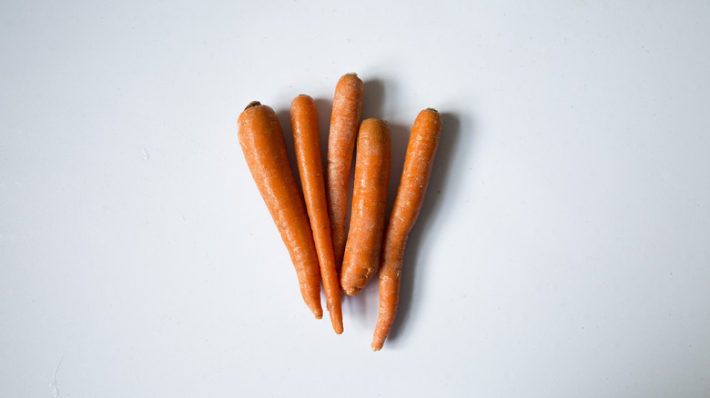 5 raw carrots on table 