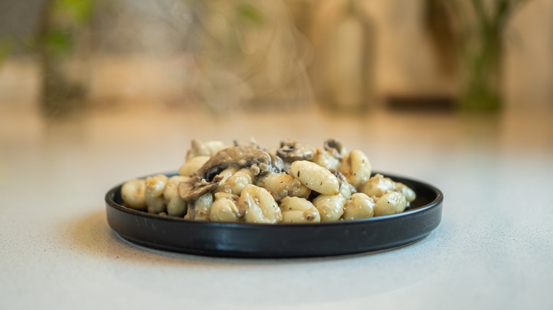 steaming gnocchi on black plate