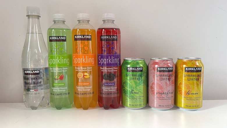 Seven Kirkland sparkling waters lined up on white table