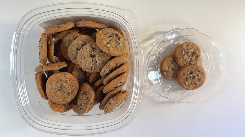 Container of Kirkland mini chocolate chip cookies next to glass plate of cookies on white background