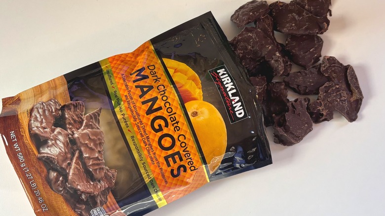 Dark chocolate mangoes spilling out of bag of Kirkland dark chocolate mangoes onto white table