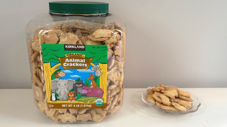 Container of Kirkland organic animal crackers next to glass plate of animal crackers on white background