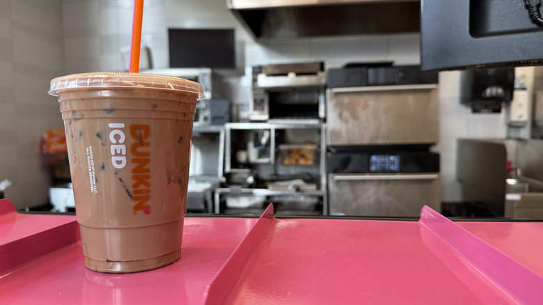 Dunkin cold brew with mocha flavor swirl on a pink counter ready for pickup.