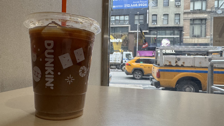 Dunkin cold brew with white chocolate flavor swirl on a pink counter ready for pickup.