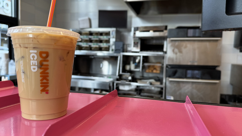 Dunkin cold brew with butter pecan flavor swirl on a pink counter ready for pickup.