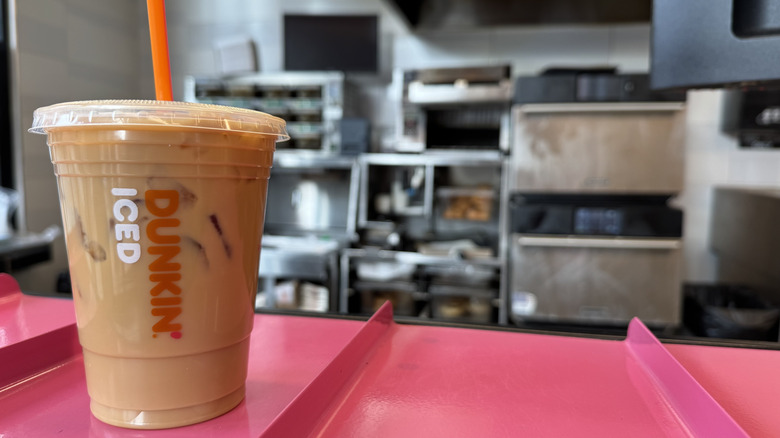 Dunkin cold brew with caramel flavor swirl on a pink counter ready for pickup.