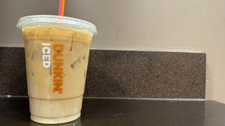 Dunkin cold brew with French vanilla flavor swirl on a pink counter ready for pickup.