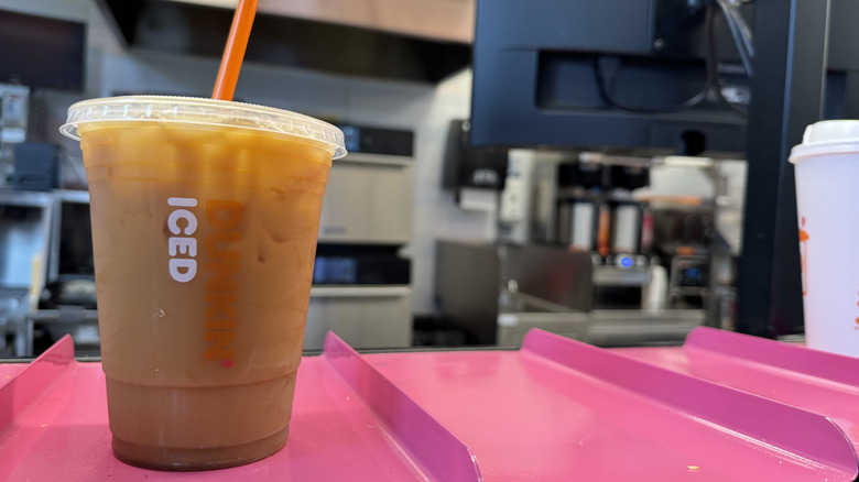 Dunkin' cold brew with brown sugar syrup flavor swirl on a pink counter ready for pickup.