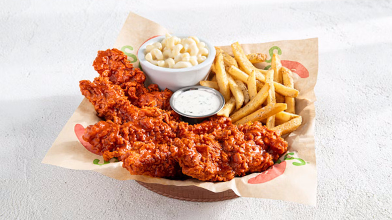 Chili's Nashville Hot Chicken Crisper Combo with six reddish crispers next to fries, a white bowl filled with macaroni and cheese, and a bowl of ranch dressing nestled in paper