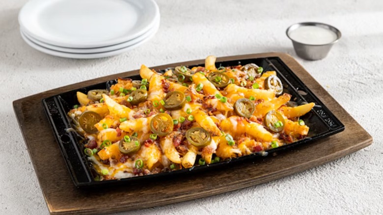 Chili's Texas Cheese Fries in a black rectangular container on a rectangular wood plate