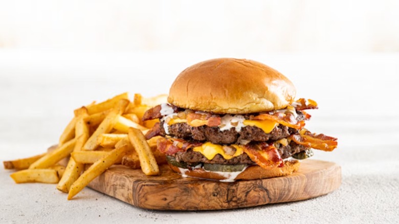 Chili's Bacon Rancher Burger on a wood plank with fries to the left