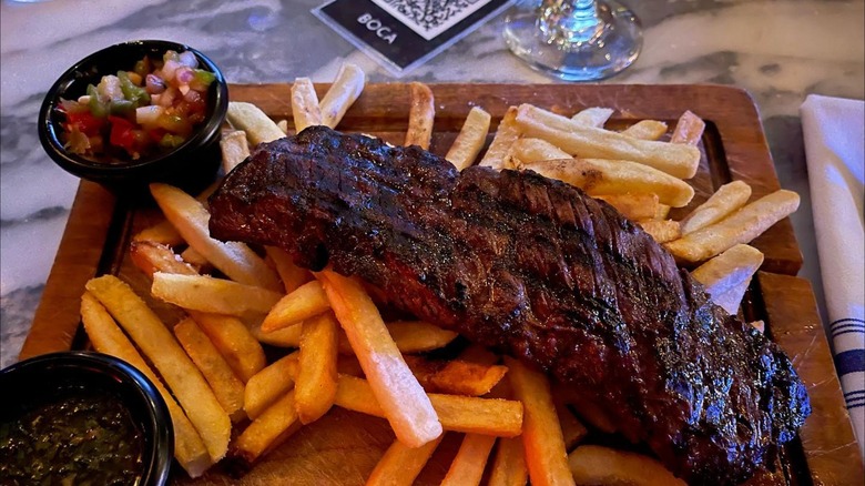 Steak and fries on a wooden cutting board at BOCA