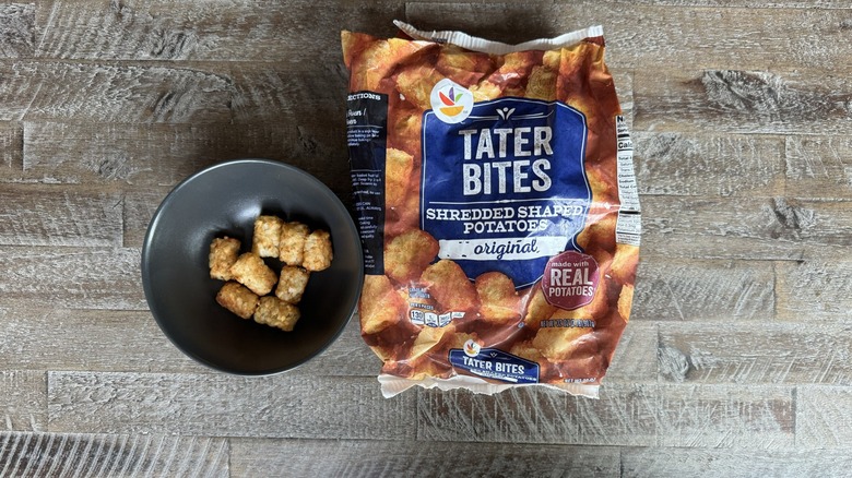 Tater tot bag on wooden surface next to bowl of tots